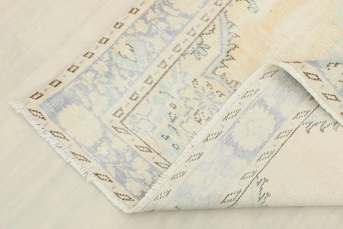 Corner of the rug folded to show the cotton foundation and reverse side
