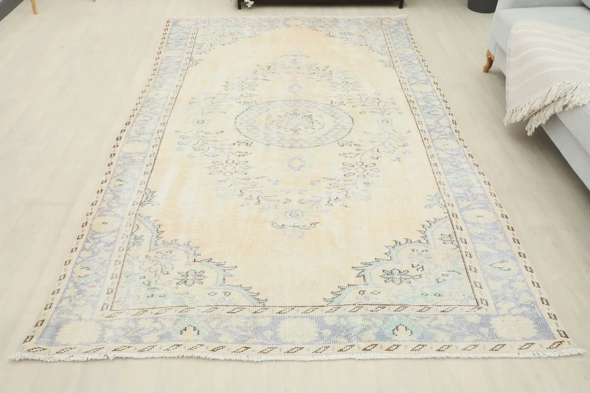 Full overhead view of the vintage ivory and blue rug laid out on a light floor
