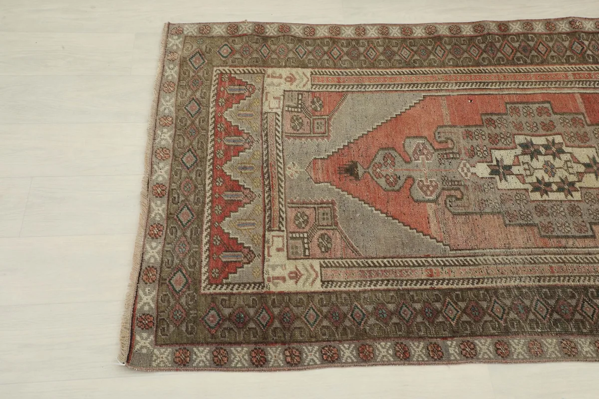 Opposite angle view of the vintage Anatolian rug, displaying its faded rust and gray tones