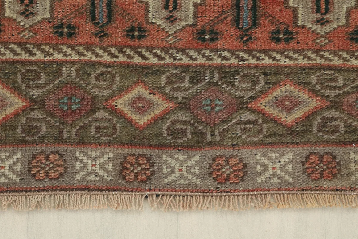Detail of the olive and beige outer border with geometric and floral-like patterns