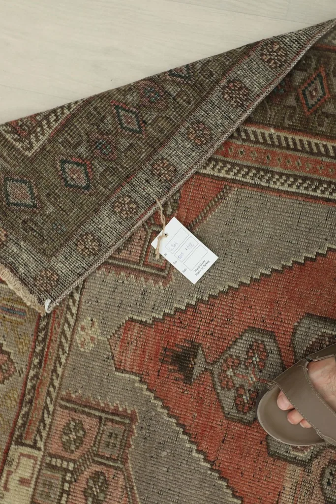 Underside of the hand-knotted rug, showing the cotton foundation and a product tag