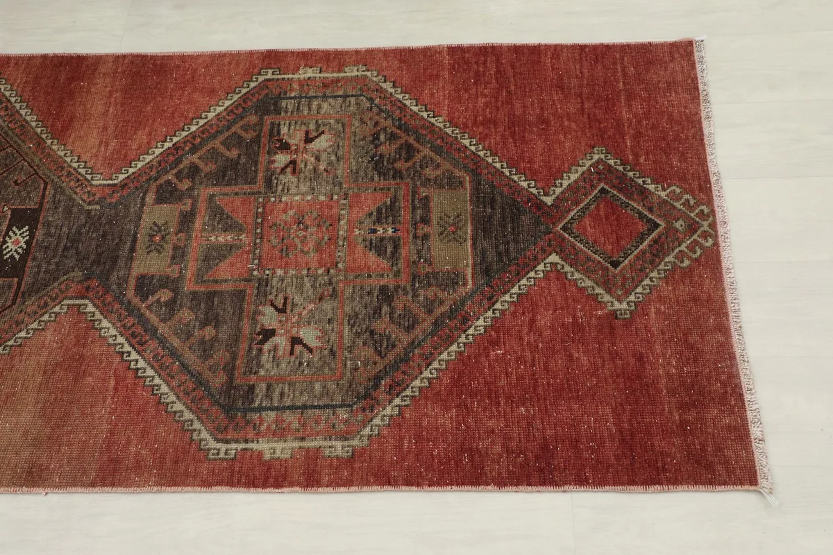 Close-up angled view of one end of the runner rug, showing the geometric medallion and color variations