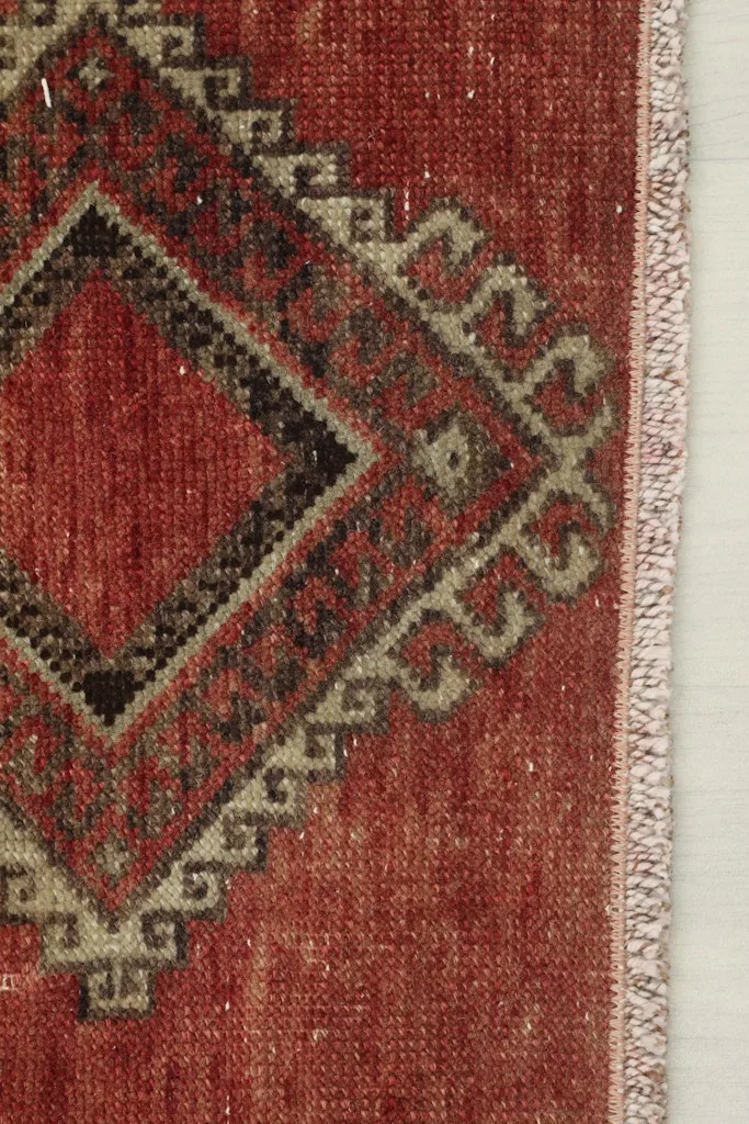 Close-up of the rug's edge and fringe, showing the rust field and part of the geometric design