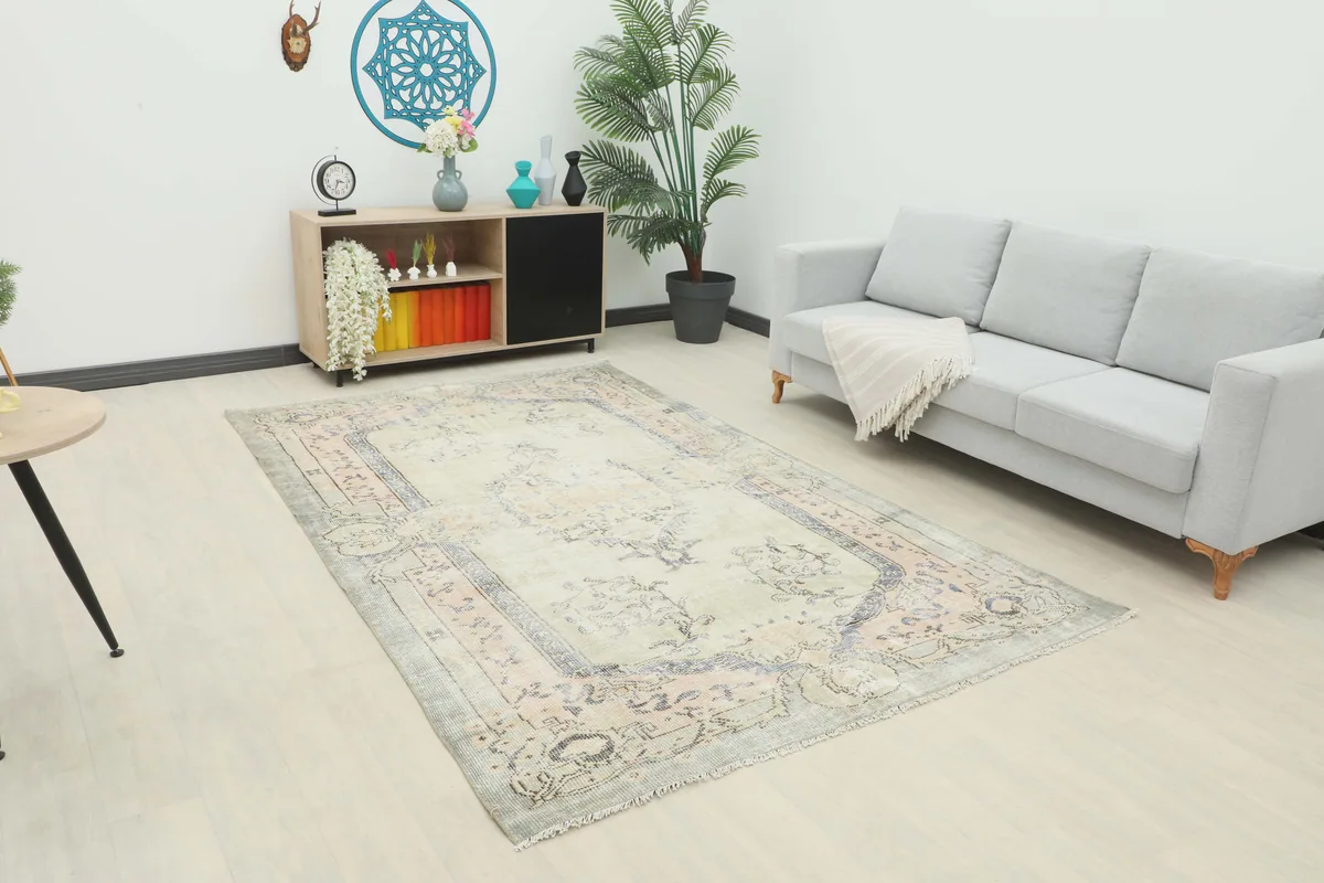 Faded Gray Rose Medallion Rug in a room setting with a light gray sofa and wooden cabinet.