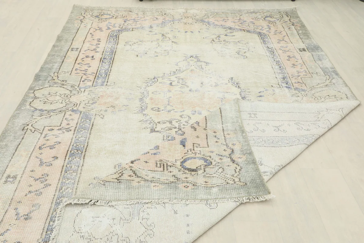 View of the Faded Gray Rose Medallion Rug folded back, revealing the reverse side of the weave.