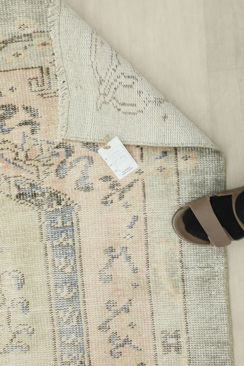 Faded Gray Rose Medallion Rug with a size tag and a foot for scale, showing texture and colors.
