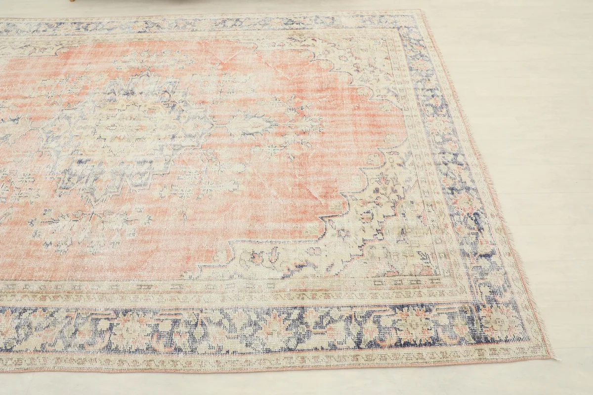 Close-up angle showing the rust medallion and navy border of the vintage rug