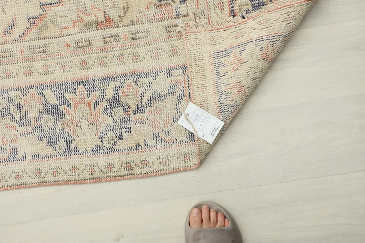 Corner of the rug with a size tag and a foot for scale