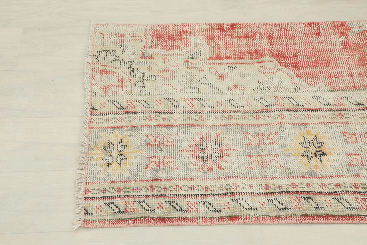 Close-up of the rug's end, showing the faded rose field blending into the beige border and fringe