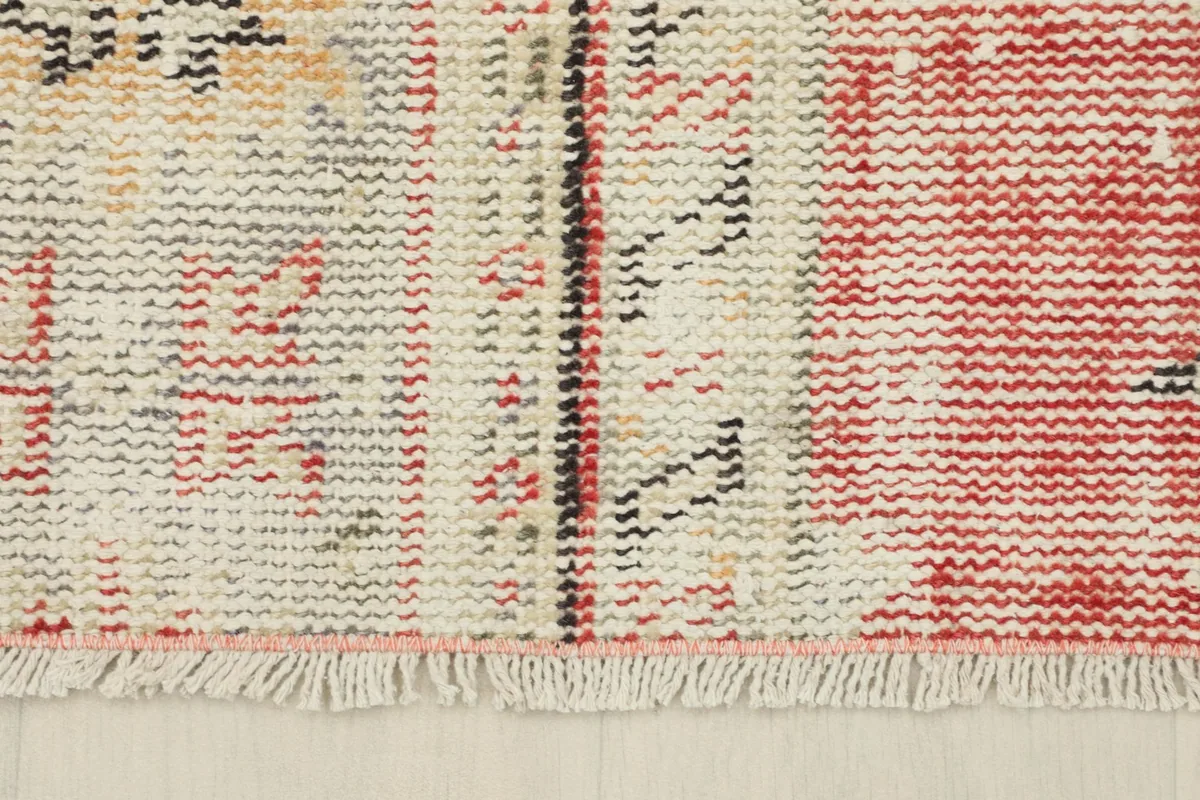 Close-up of the rug's end, showing the short, natural cotton fringe and the edge of the pile