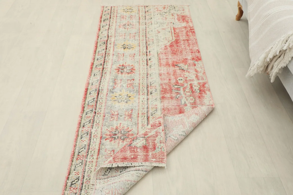 View of the rug partially folded, showing the flexibility and thickness of the vintage wool construction