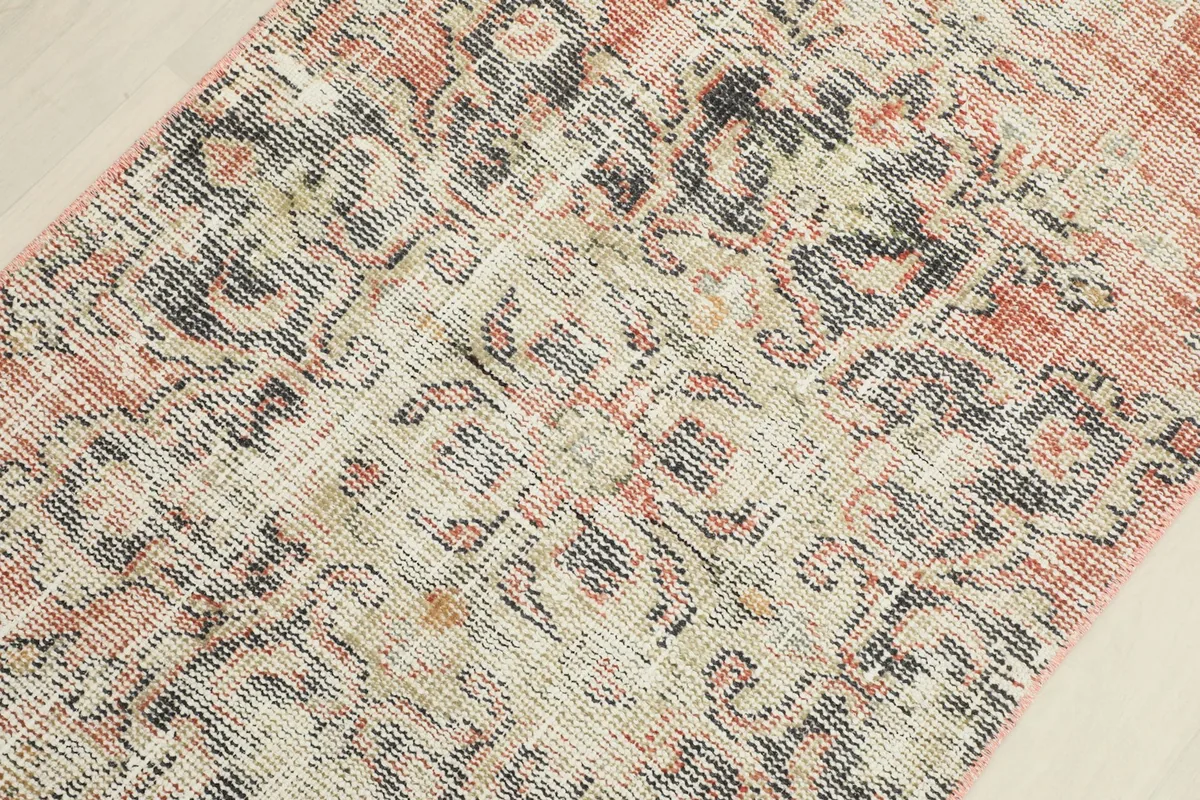 Detailed view of the rug's central pattern, revealing intricate floral elements and signs of wear