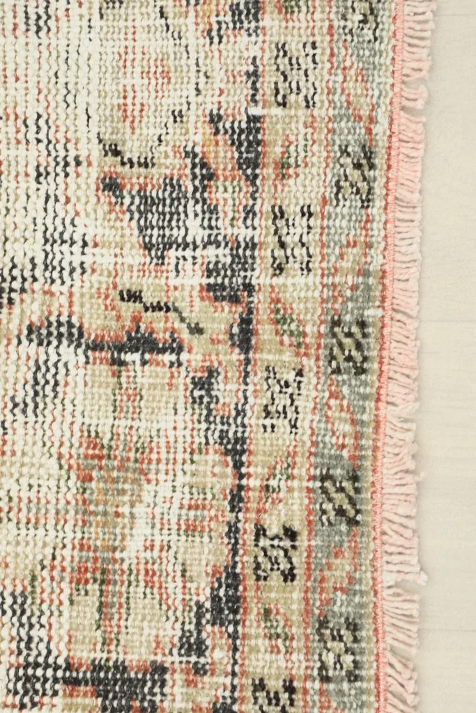 Detail of the rug's edge and border, showing fringe and distressed patterns