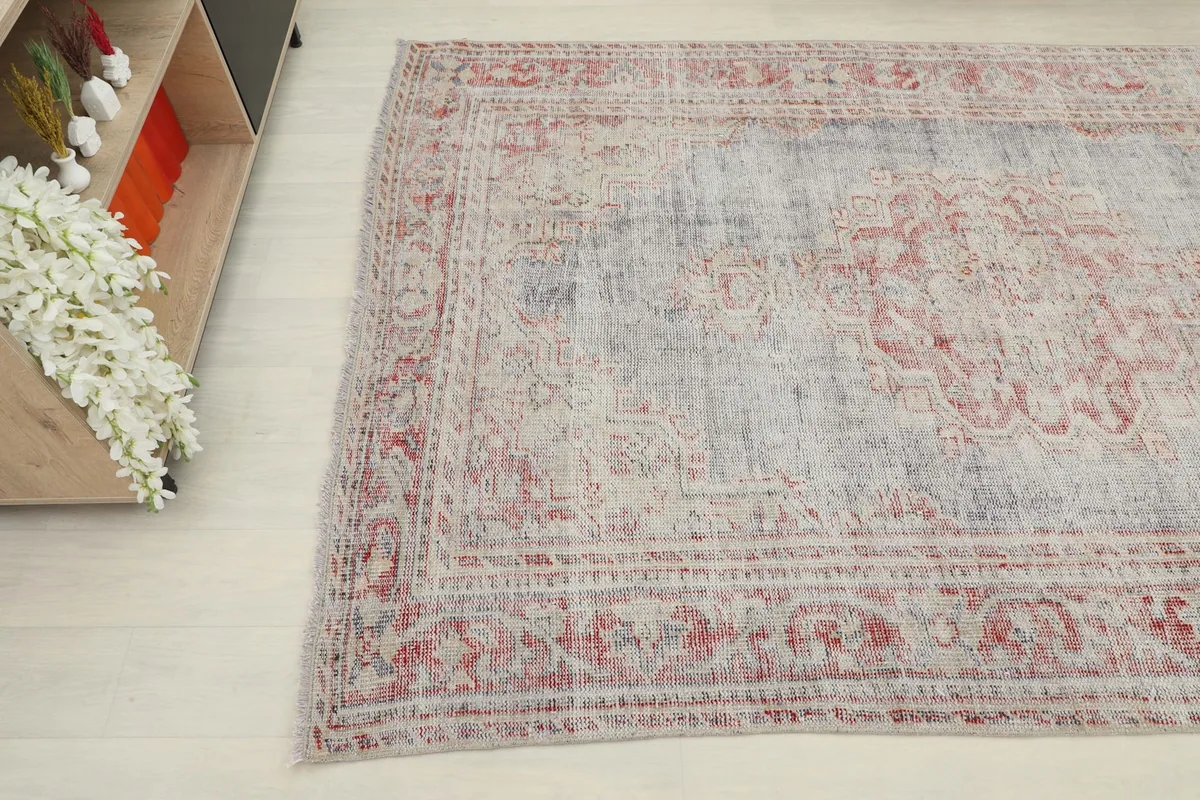 Corner view of the hand-knotted rug, highlighting the distressed rose and ivory patterns