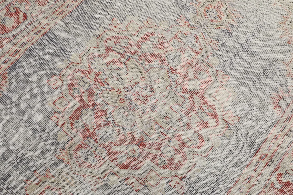 Close-up of the central medallion motif in rose and ivory on the gray vintage rug