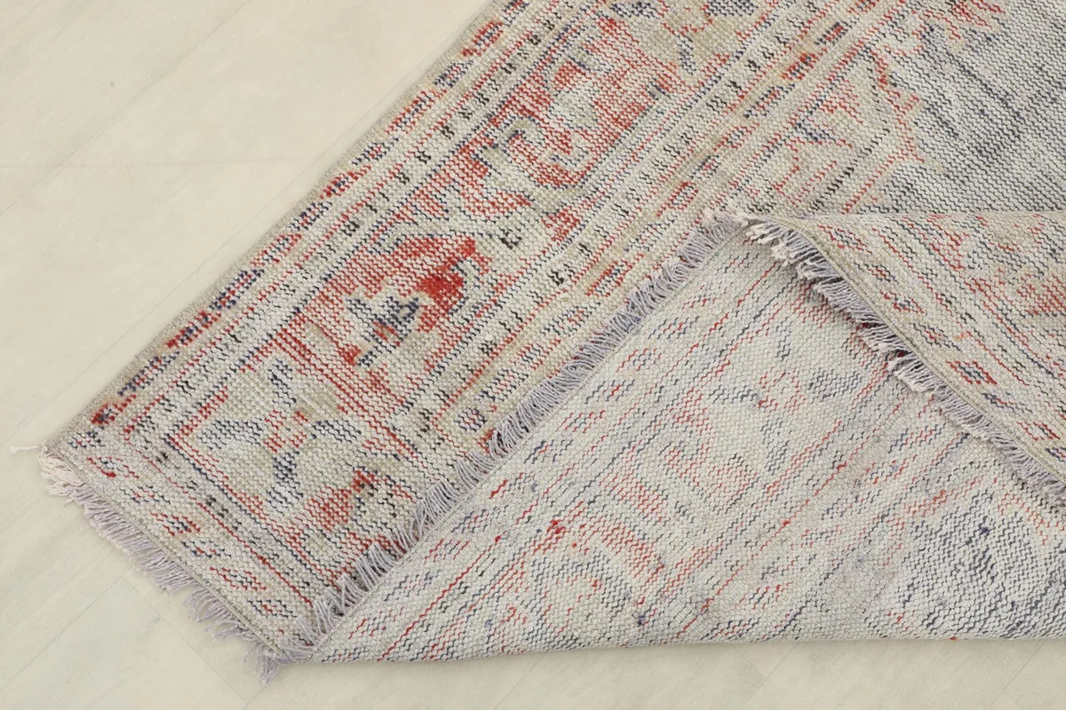 Corner of the vintage rug folded back to reveal the cotton foundation