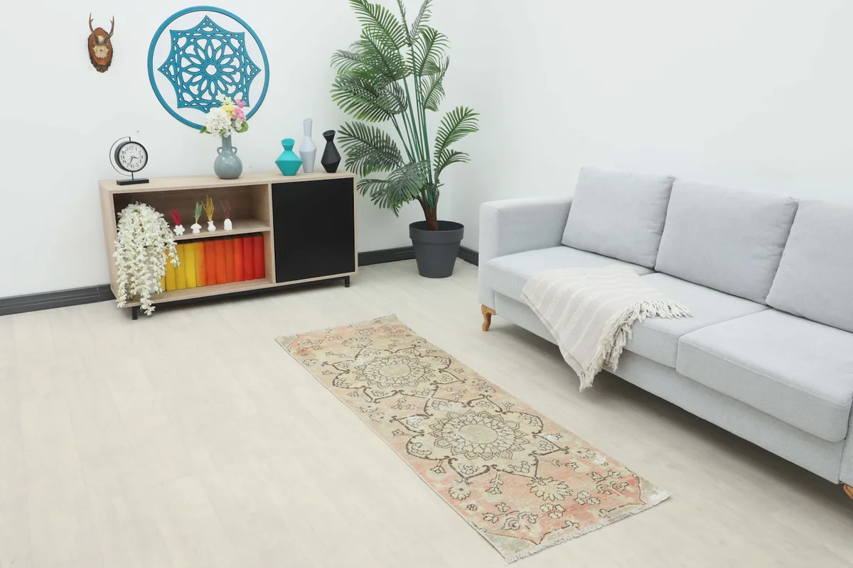 Vintage rose and beige runner rug in a modern living space with a couch and console table.
