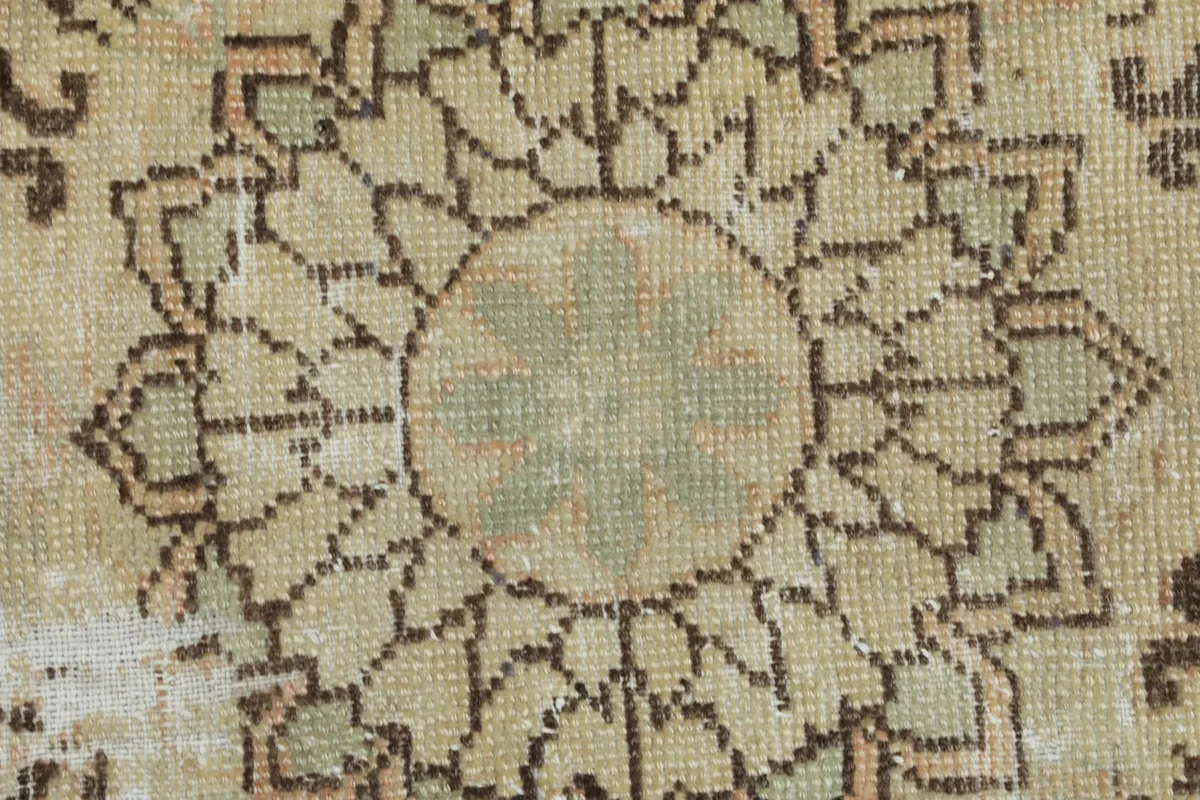 Extreme close-up of the low wool pile and detailed stitching of a medallion pattern.