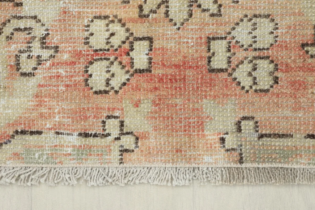 Close-up of the rug's short, natural cotton fringes and the hand-knotted edge.