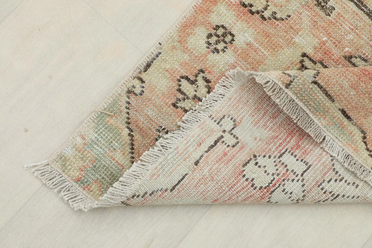 Corner of the rug folded back, showing the cotton foundation and the reverse side.