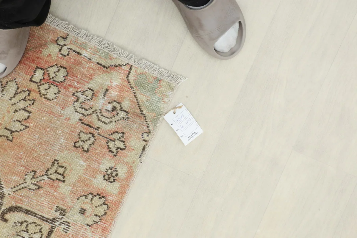 Overhead view of the rug's end with a size tag and feet for scale.