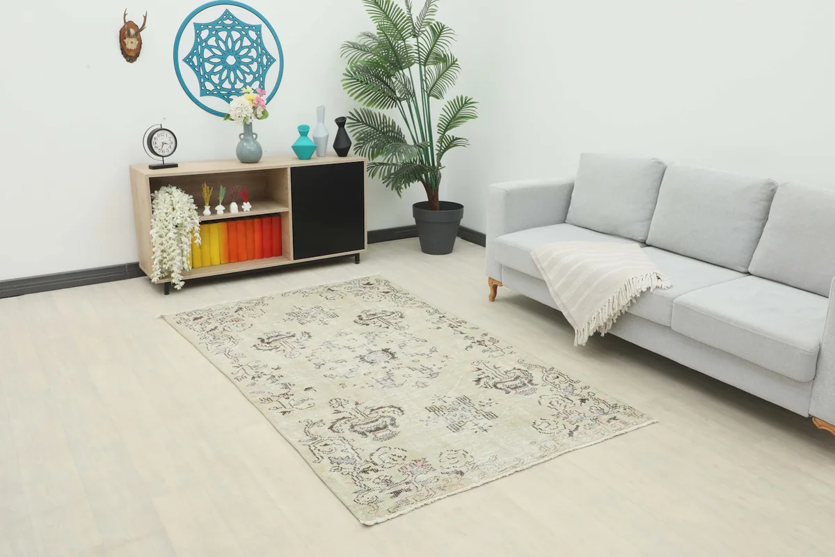 Vintage beige rug displayed in a living room setting with a light gray sofa and wooden cabinet