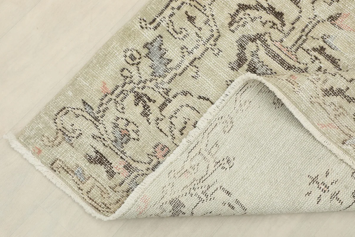 Corner of the rug folded back to show the cotton foundation and reverse side of the hand-knotted work