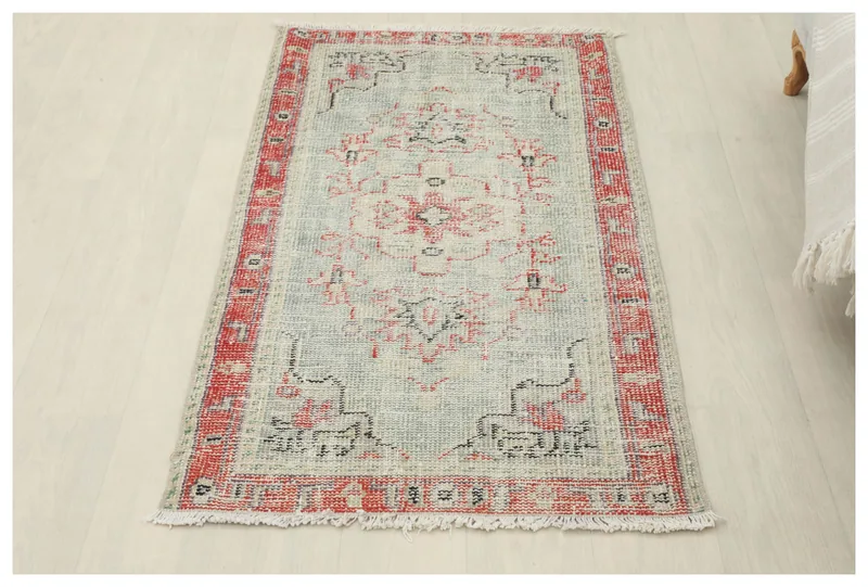 Full overhead view of the gray and red vintage Anatolian area rug on a white background
