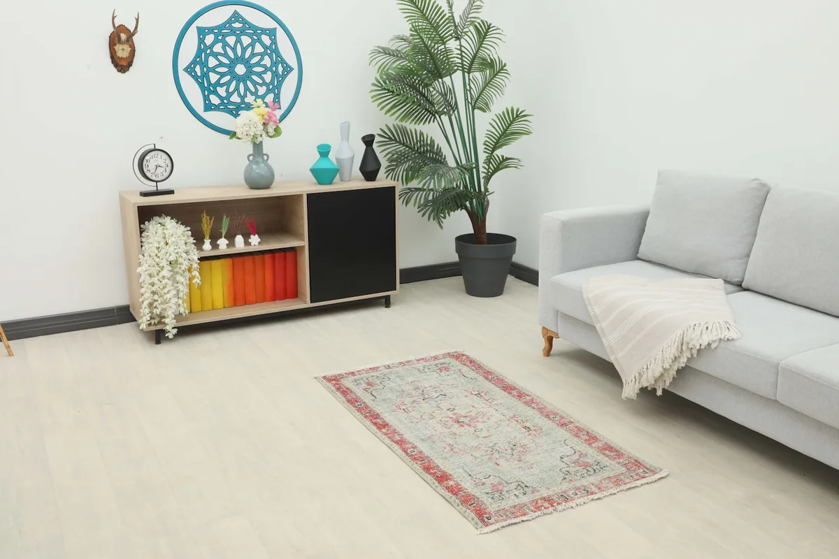 Vintage gray and red rug placed in a living room setting with a sofa and cabinet