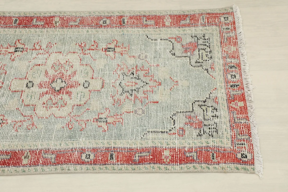 Close-up view of the upper right section of the rug, showing faded red border and gray field