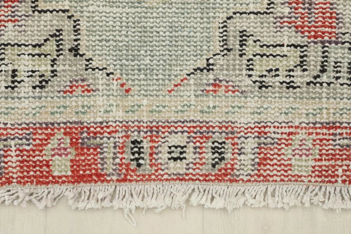 Close-up of the short fringe and the distressed red border at one end of the rug