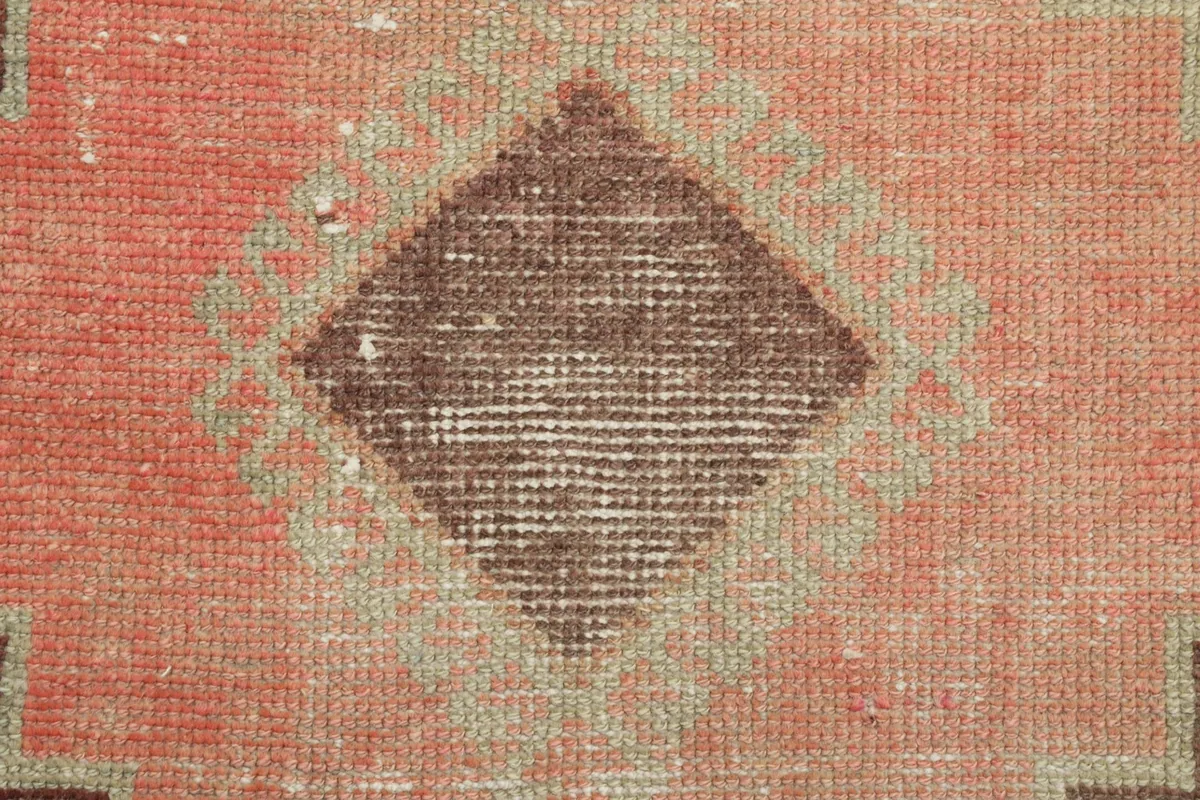 Close-up of the wool pile texture within a rust-colored diamond motif