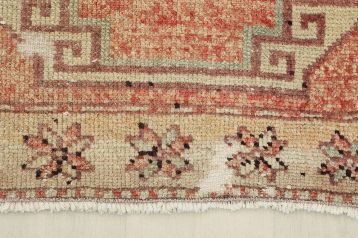 Detail of the rug's border with small floral-like motifs on a beige background