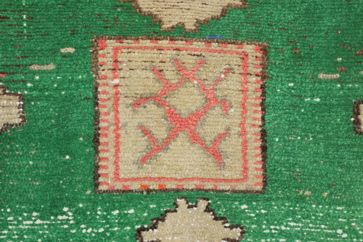 Close-up of a green field with a red and beige central geometric design