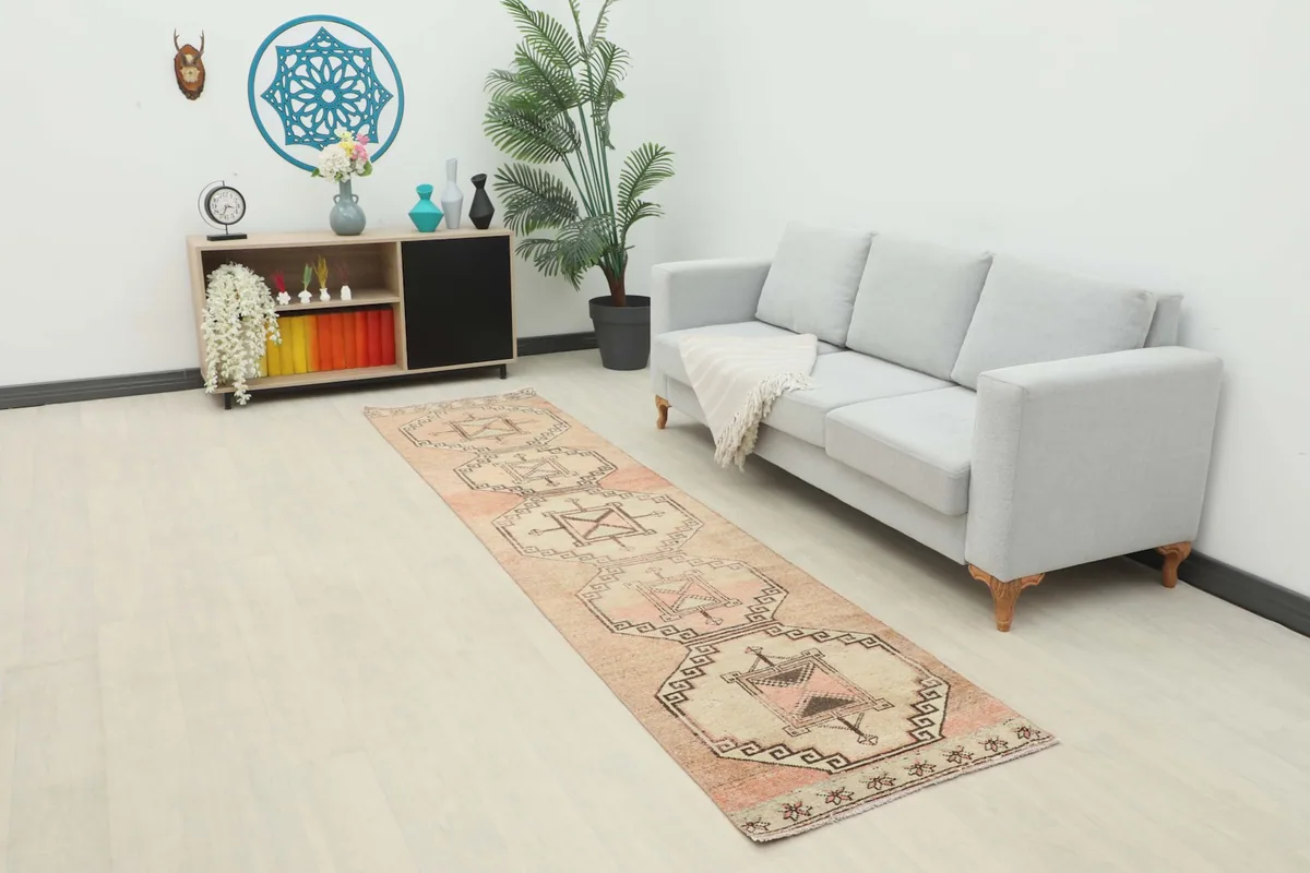 Beige and rust runner rug displayed in a living room setting, extending along a light-colored floor next to a sofa