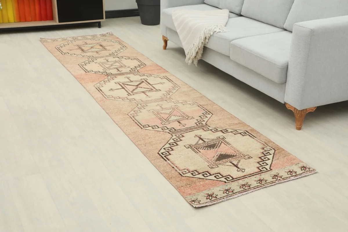 Angled view of the vintage runner rug in a room, highlighting its length and geometric design next to modern furniture