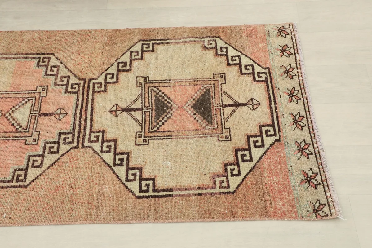 Close-up of a geometric medallion motif on the beige field, showing the intricate black and rust details