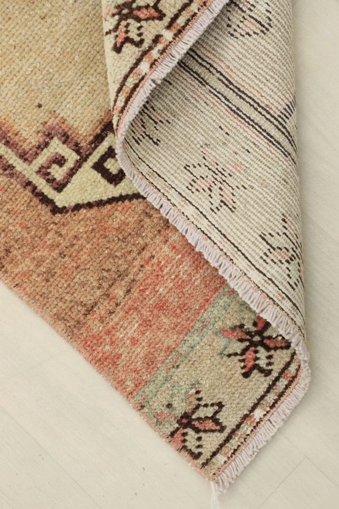 View of the rug's underside and folded edge, showing the cotton foundation and tight weave