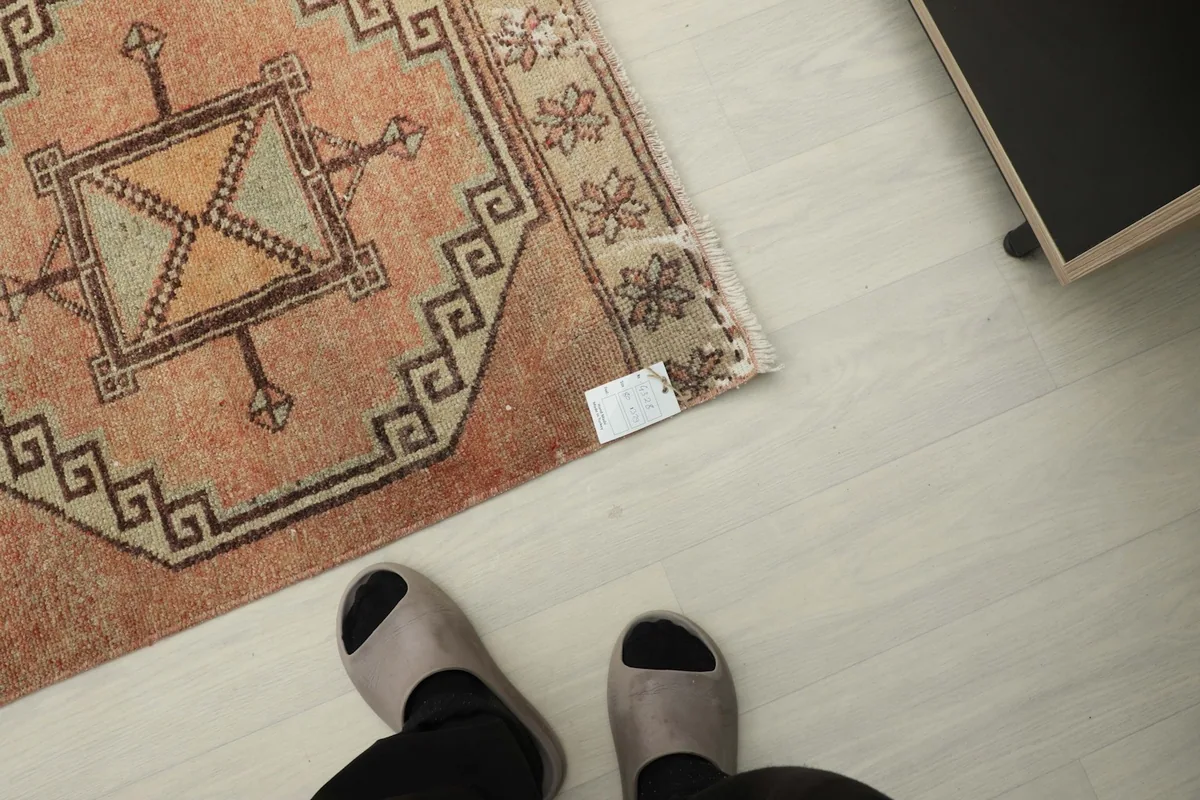 Overhead view of a section of the runner rug on the floor, with feet visible for scale