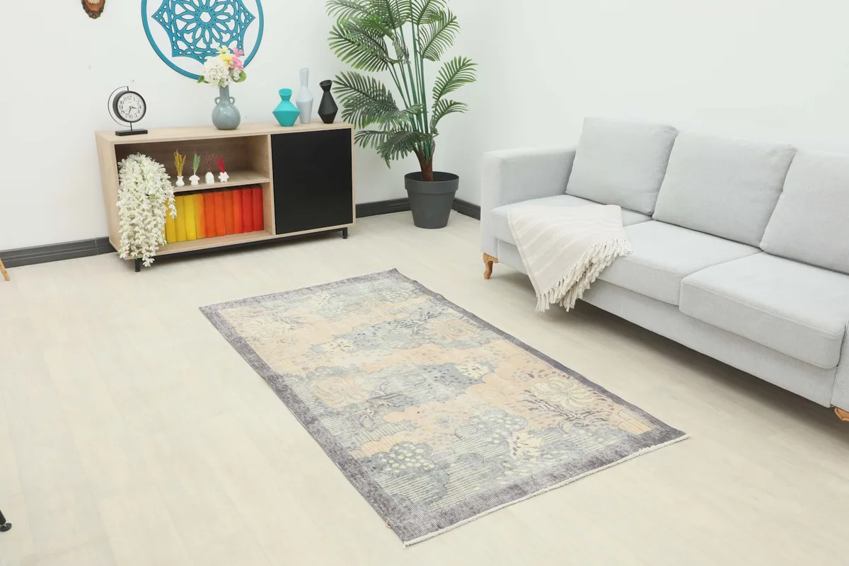 Vintage area rug displayed in a living room setting with a light gray sofa and wooden cabinet.