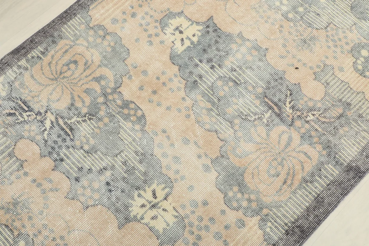 Detailed view of the rug's central pattern, featuring beige and gray floral shapes.