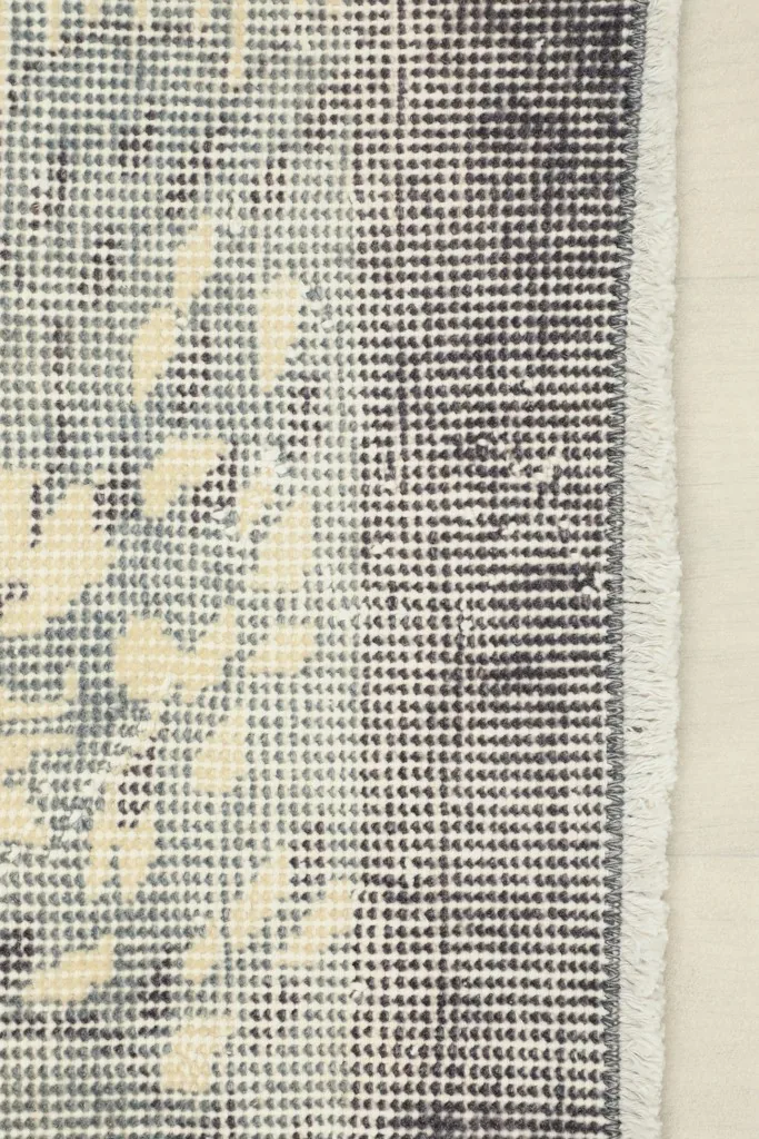 Close-up of the rug's short fringe and the distressed gray border design.