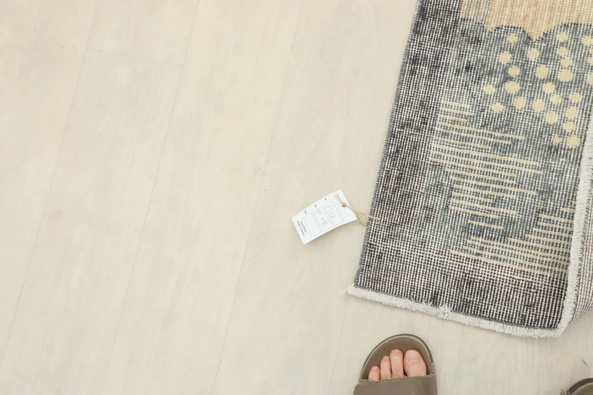 View of the rug's back, showing the hand-knotted construction and a small tag.