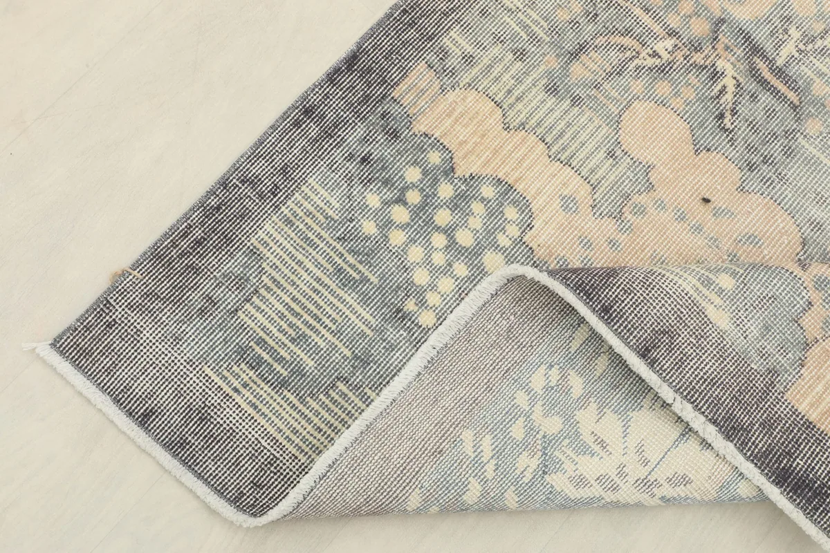 Corner of the rug folded back, showing the cotton foundation and the reverse side.
