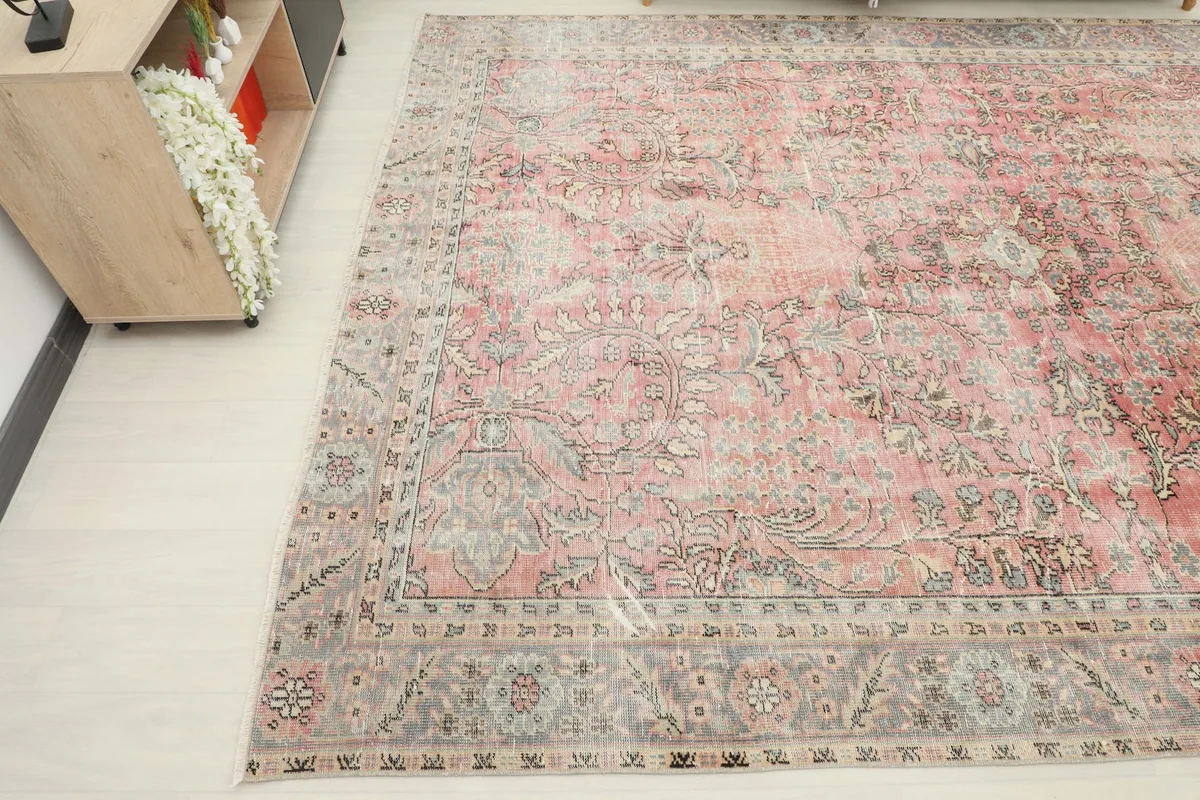 Diagonal view highlighting the distressed rose and gray colors and intricate floral patterns of the rug