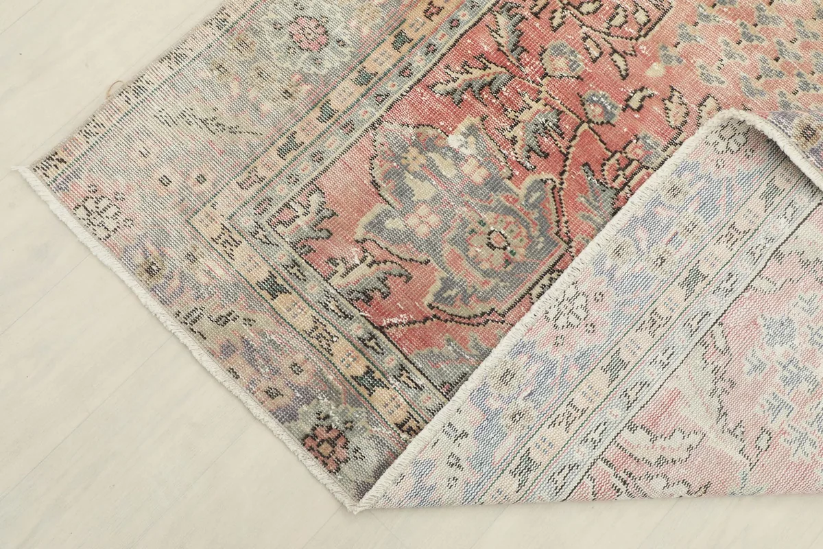 Corner of the rug folded back to reveal the cotton foundation and the reverse side of the hand-knotted design