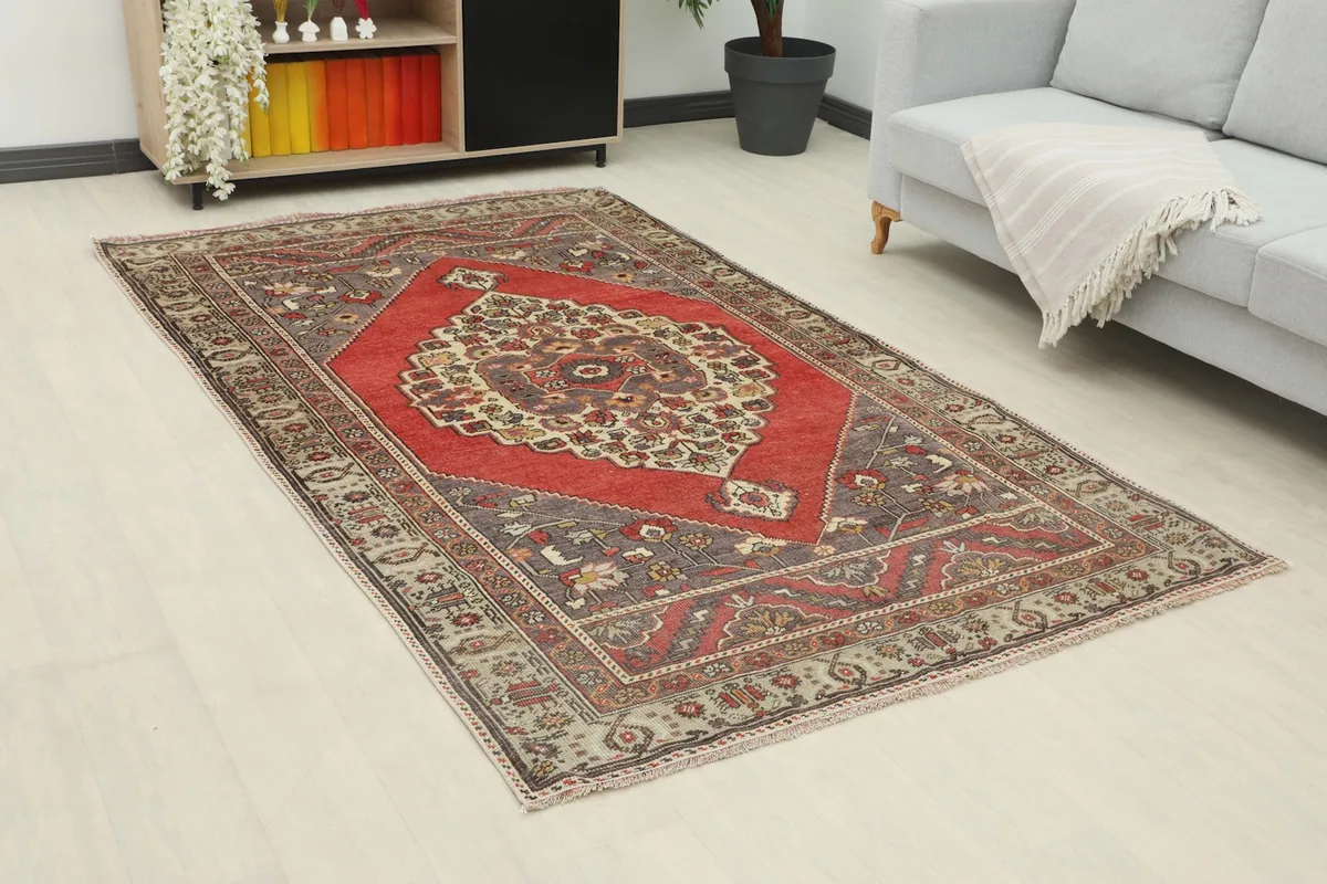 Angle view of the hand-knotted wool rug in a living room, highlighting its red medallion and gray border.