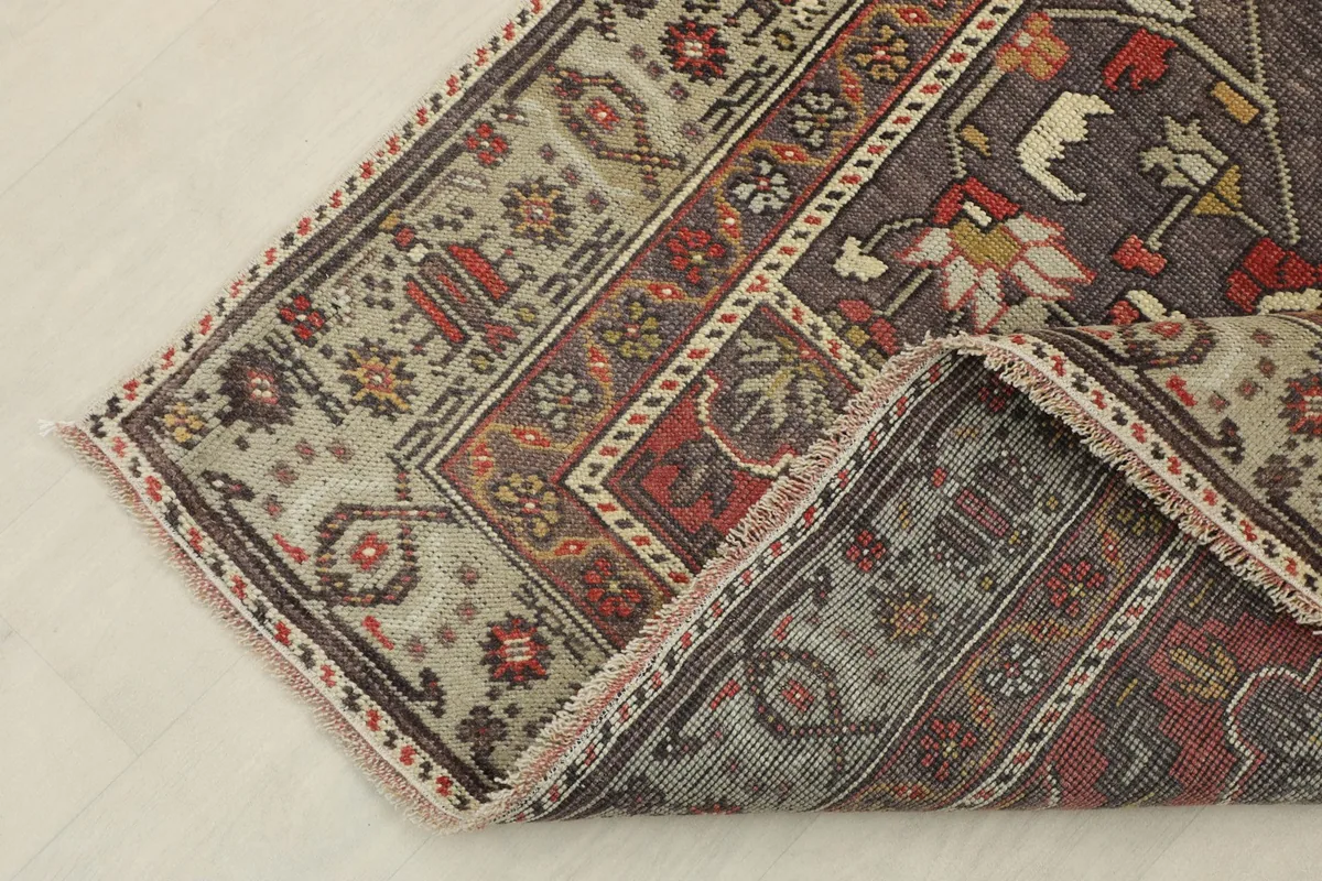 View of the rug's underside and corner, showcasing the cotton foundation and hand-knotted construction.