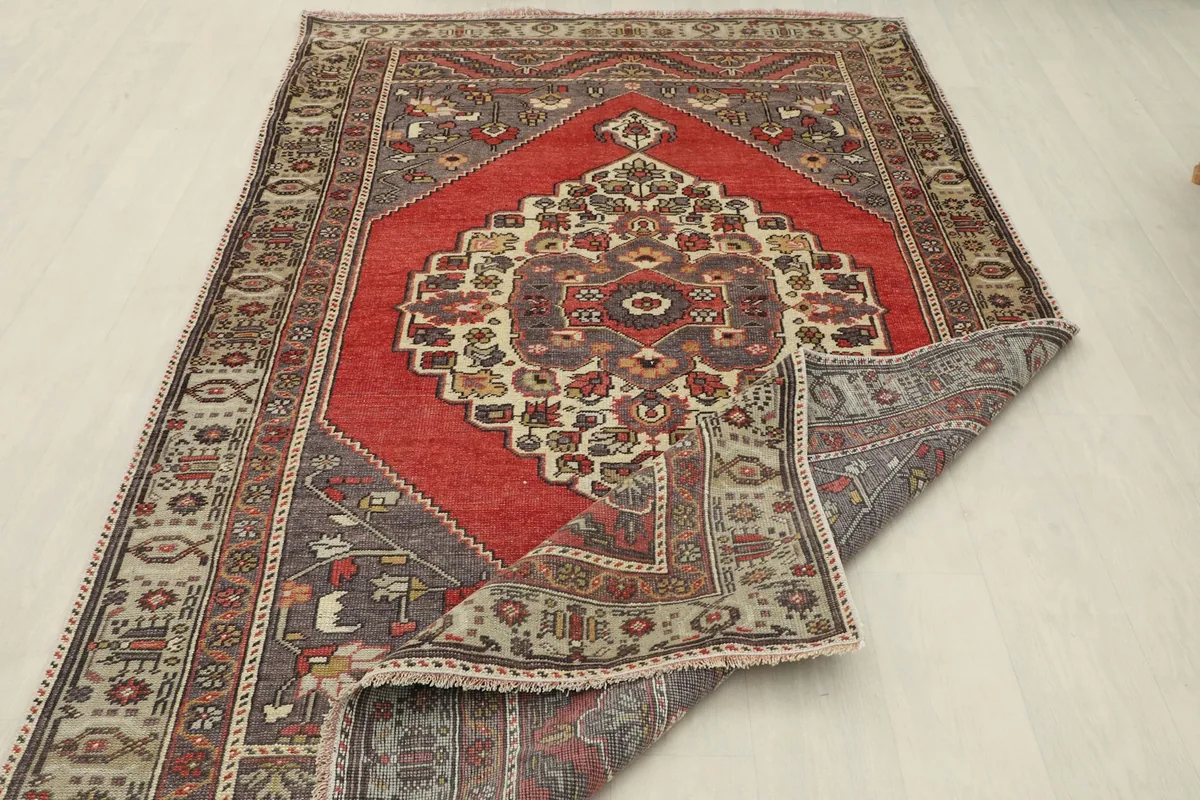 The rug partially folded back, revealing the reverse side and confirming its authentic vintage hand-knotted structure.