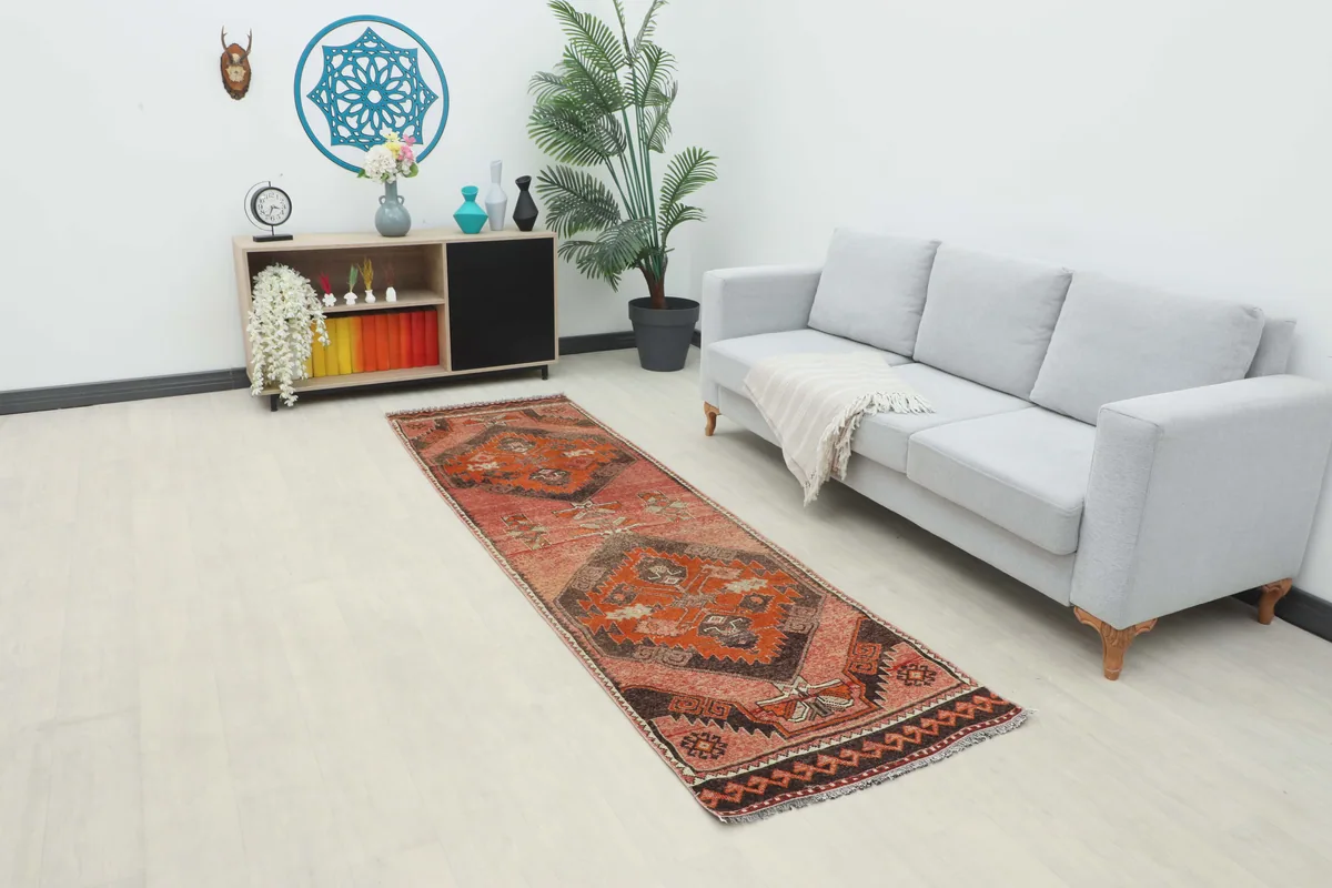 Rose Orange Geometric Anatolian Runner placed in a living room setting next to a sofa.
